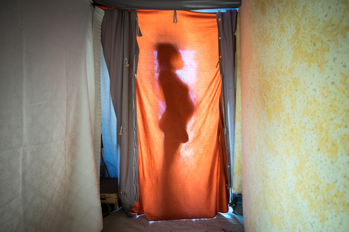 Life goes on. An asylum seeker from Mali who is pregnant, portrayed at the entrance of her tent in the camp where she lives with her husband